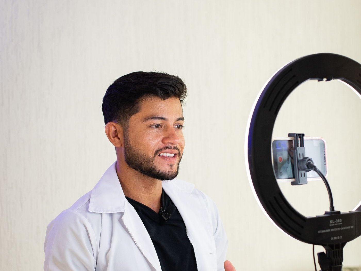 Doctor in a white coat recording a video with a ring light and smartphone