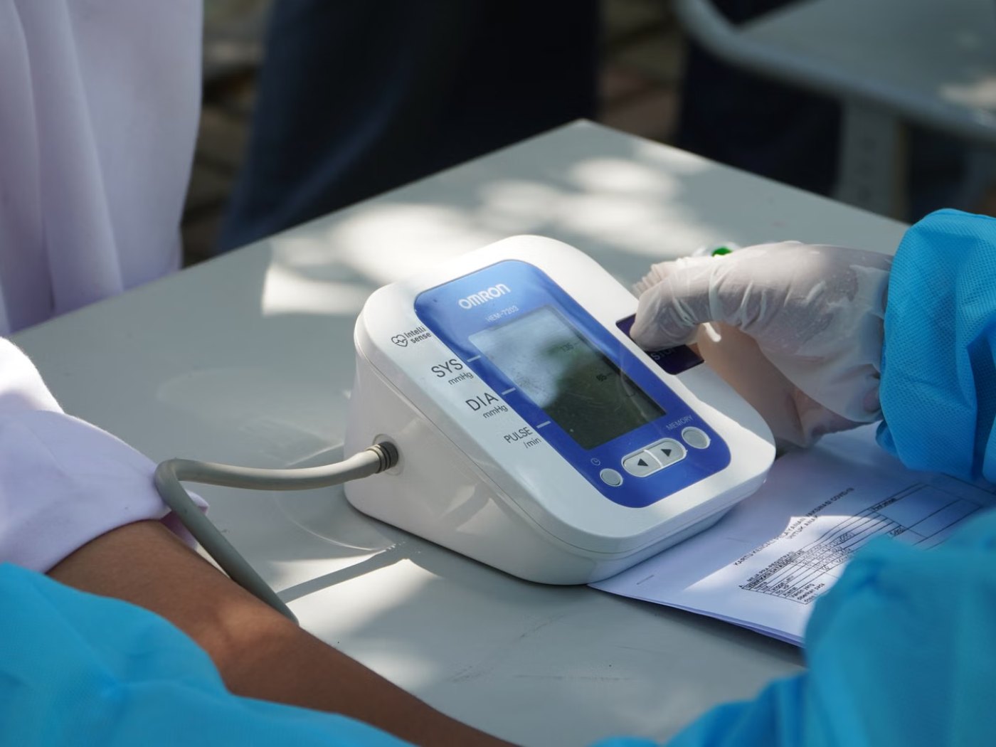 Healthcare workers carrying out blood pressure checks at an outdoor community screening